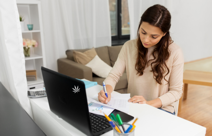 a young woman reviewing documents and charts at home next to a laptop