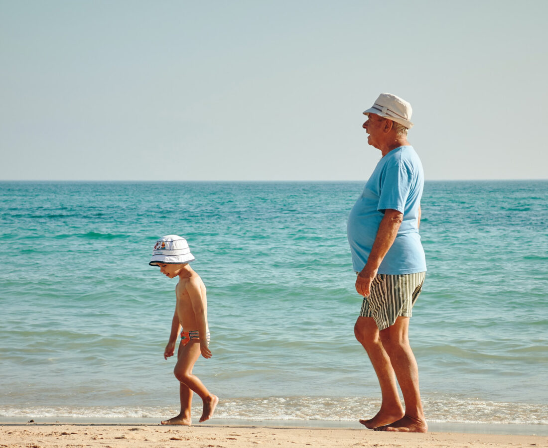 a grandpa and grandson walking down the beach