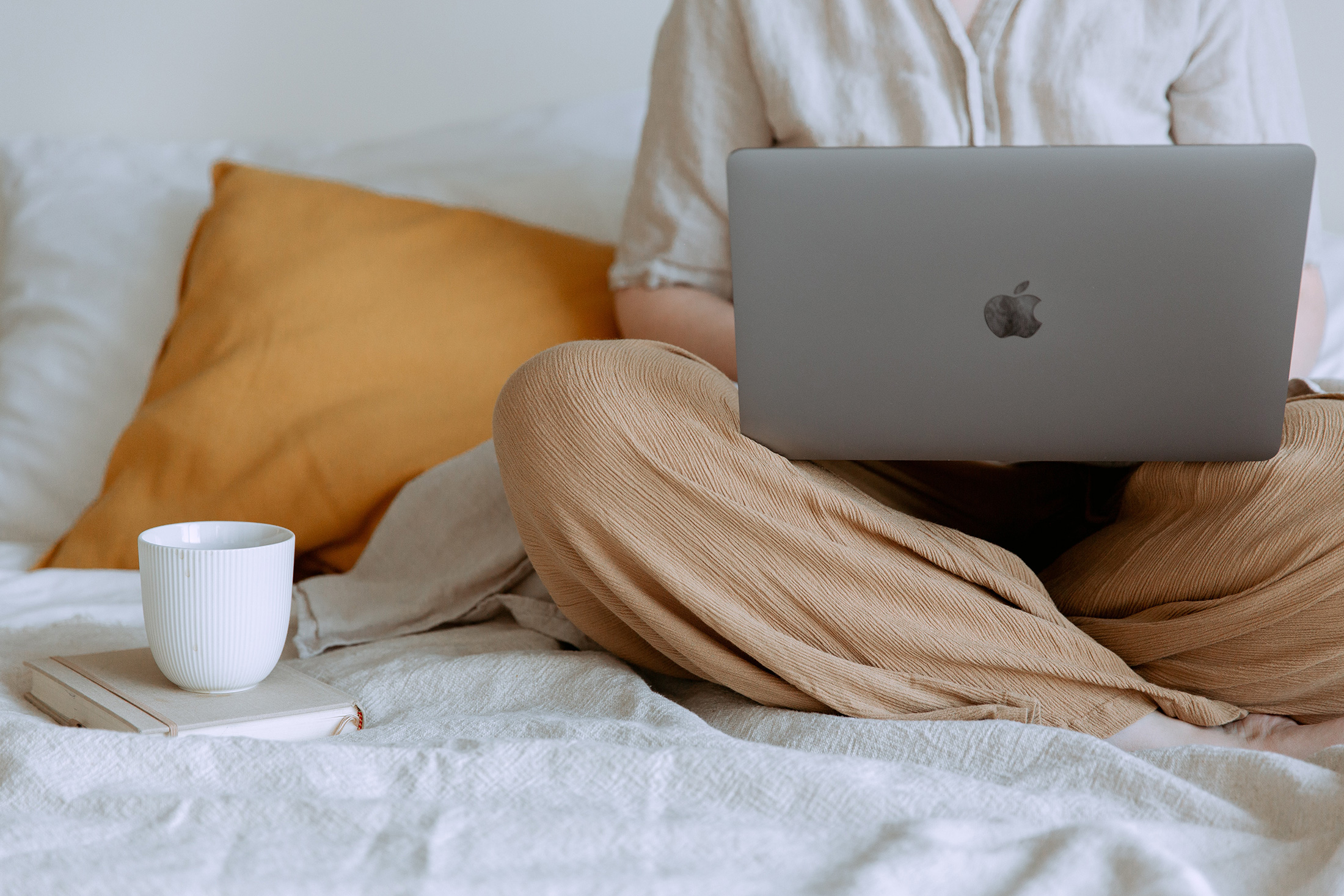 a young professional working on a laptop in bed