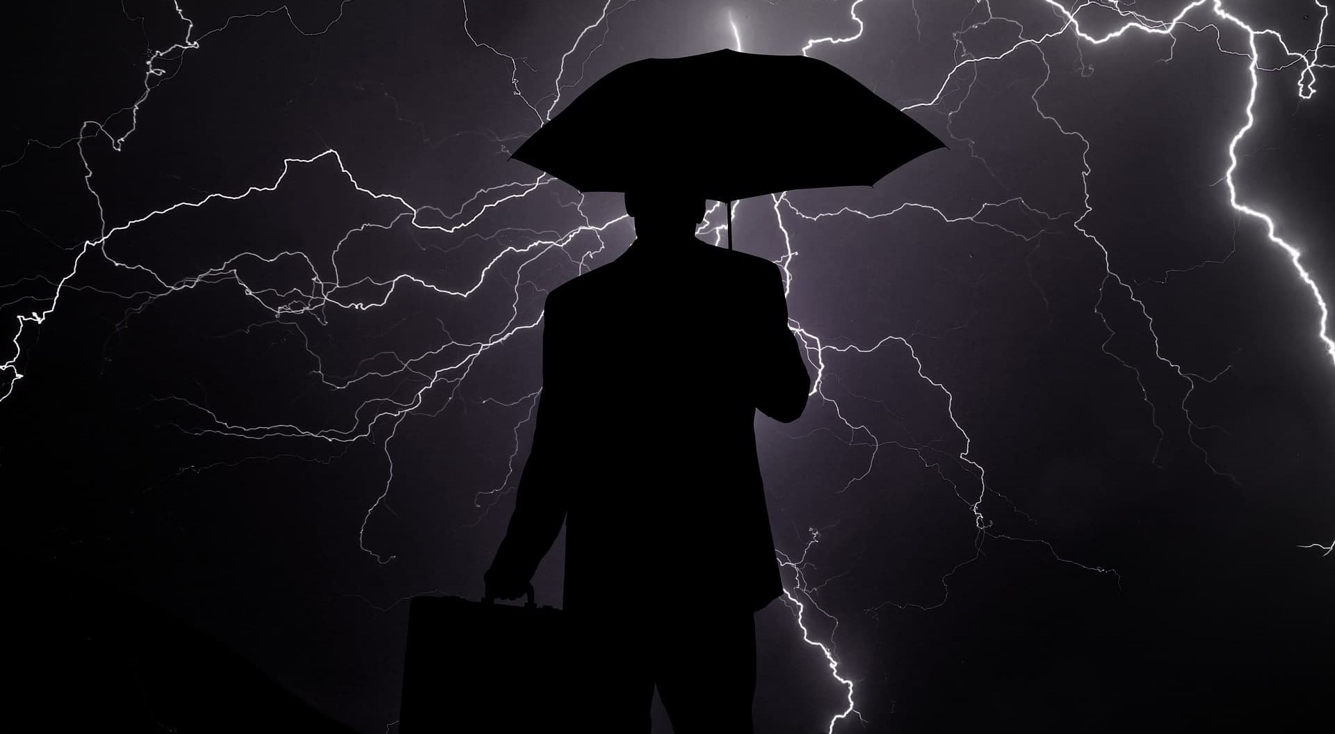 the outline of a man with an umbrella during a lightning storm