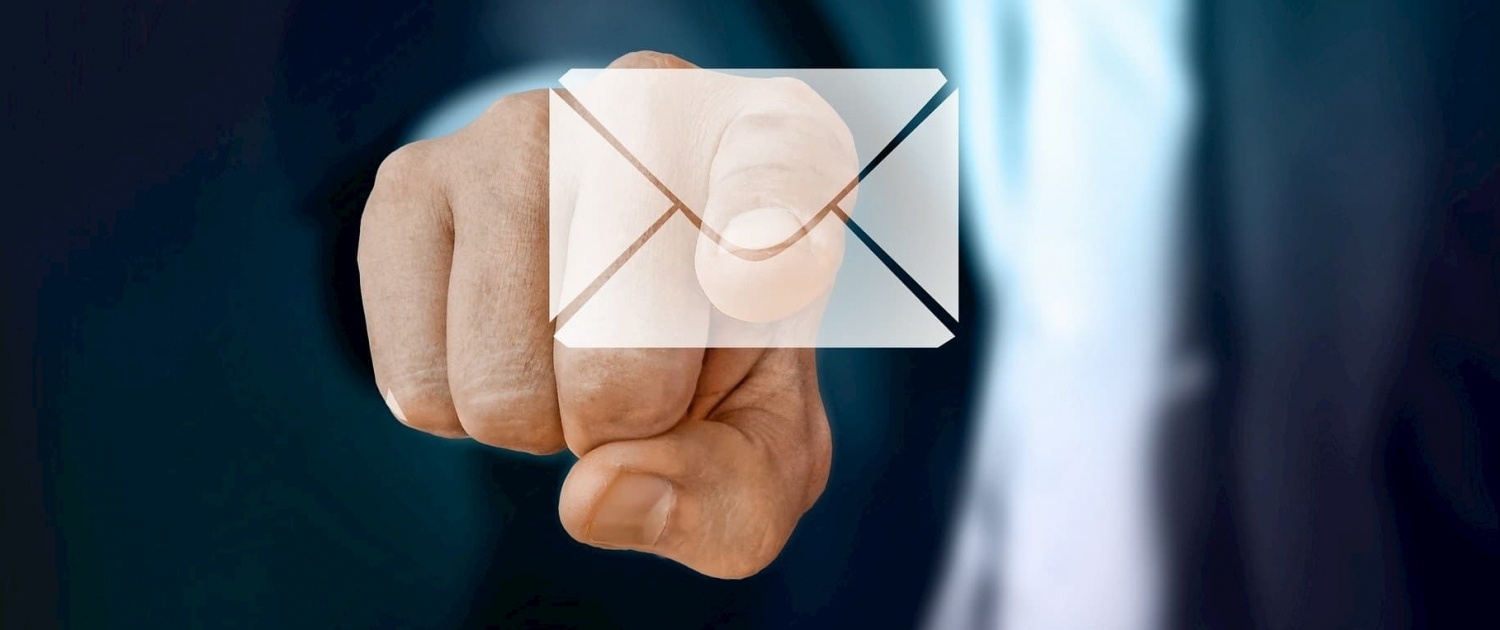 a person pointing to the symbol of a message in the foreground symbolizing email