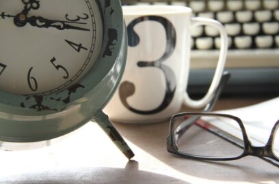 an analog clock, a coffee mug, and glasses
