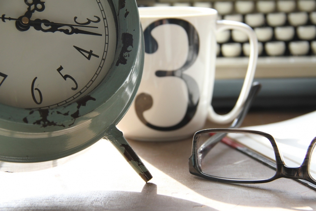 an analog clock, a coffee mug, and glasses