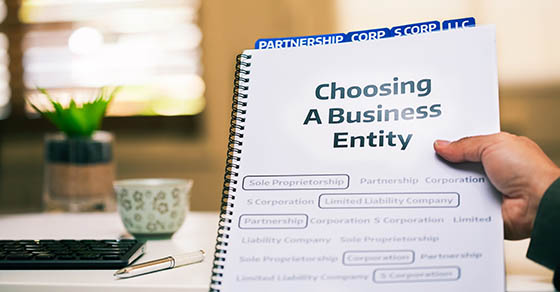 A document on different types of business formations being read by a small business owner while sitting in office desk.
