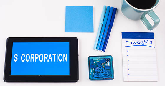 Picture of table with a tablet that has S Corporation text on it with various office supplies to the side.