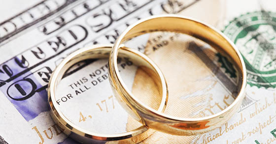 2 wedding rings overlapping each other sitting on top of cash