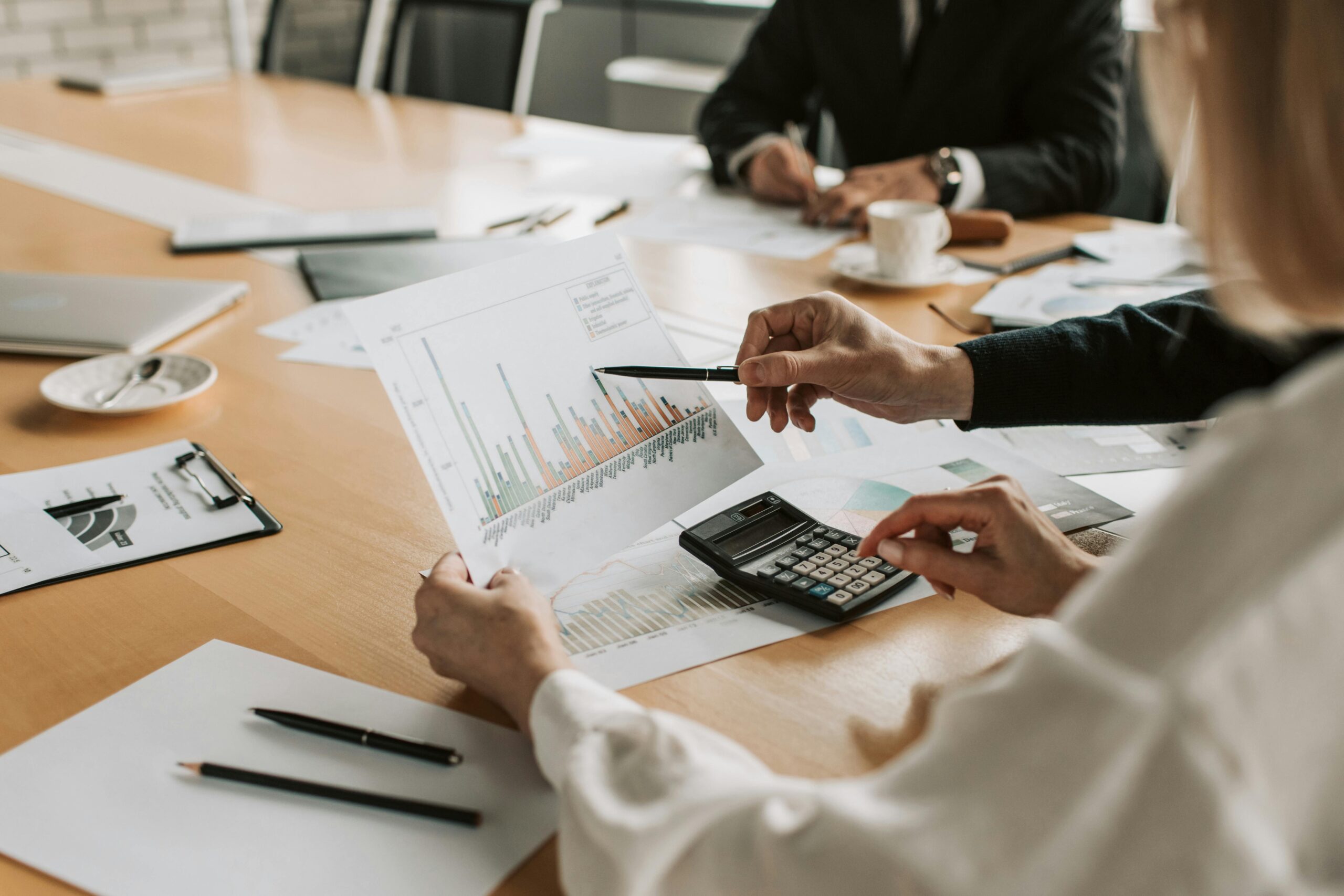 Business meeting with financial advisors reviewing market graphs and documents.