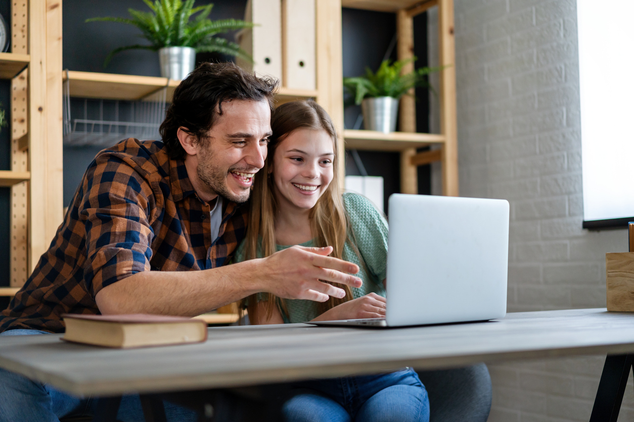 A parent and child reviewing financial information on a laptop