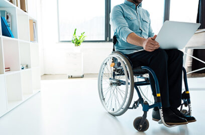 Man sitting in wheel chair with laptop, home office setting