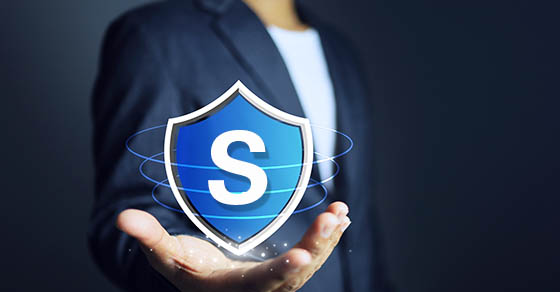 Businessman holding a shield in his hand to mean protecting data or assets from damage or theft or cyber threats