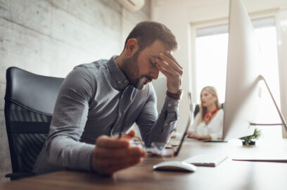 Stressed businessman sitting in an office desk and rubbing his forehead