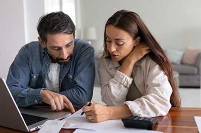Married couple, reviewing documents, laptop on desk.