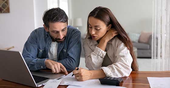 Married couple, reviewing documents, laptop on desk.