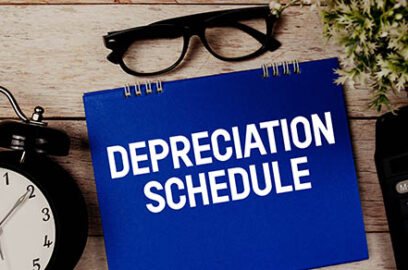 Depreciation,Schedule,Text,With,Alarm,Clock,And,Calculator,On,Wooden