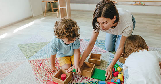 Young,Woman,Teacher,Playing,In,A,Kindergarten,With,Children,On