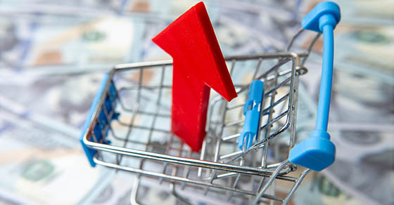 A,Shopping,Cart,And,Red,Upward,Pointing,Arrow,On,A, bed, of, lurred, one, hundred,u.s.,dollar,bills,increasing,costs,consumer,spending,concept