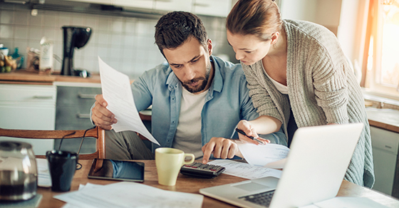 Two people, Male and female, reviewing documents, observing Desk, Laptop, Coffee