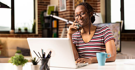 Self,Employed,Woman,Sits,At,Desk,,Multitasking,,Speaks,With,Clients