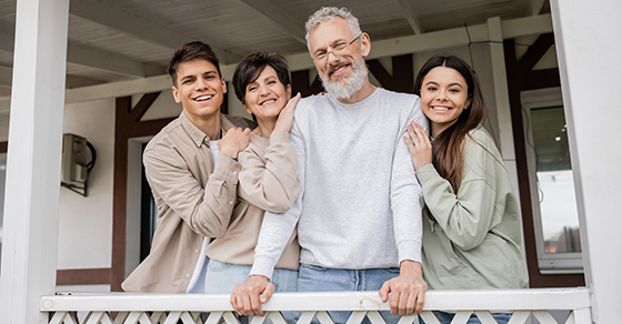 family of four, hugging, outdoors, on patio,