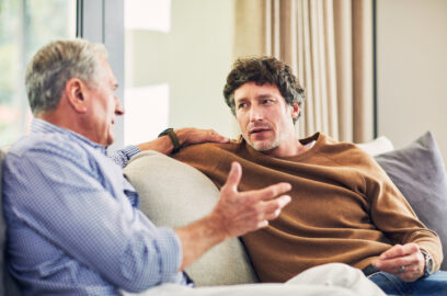 Man talking to senior father on the sofa
