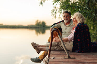 Senior couple relaxing on a pier, sharing a blanket and enjoying the sunset over the lake