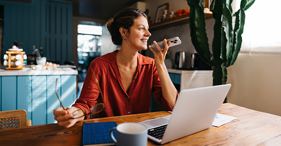 Working, remote, woman, sitting, at, home, desk, laptop, in, front, of her, talking, on the phone