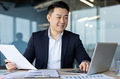 Office setting, man, reviewing documents, checking laptop, reviewing stock, before, year-end