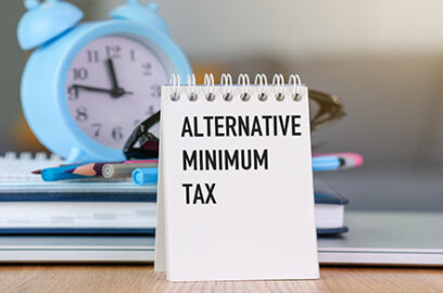 Notepad, textL Alternative Minimum Tax, sitting on desk, clock