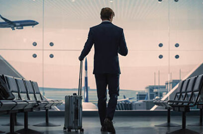 Airport,Terminal:,Businessman,With,Rolling,Suitcase,Walks,,Uses,Smartphone,App
