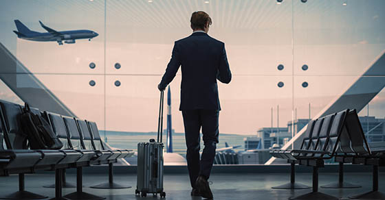 Airport,Terminal:,Businessman,With,Rolling,Suitcase,Walks,,Uses,Smartphone,App